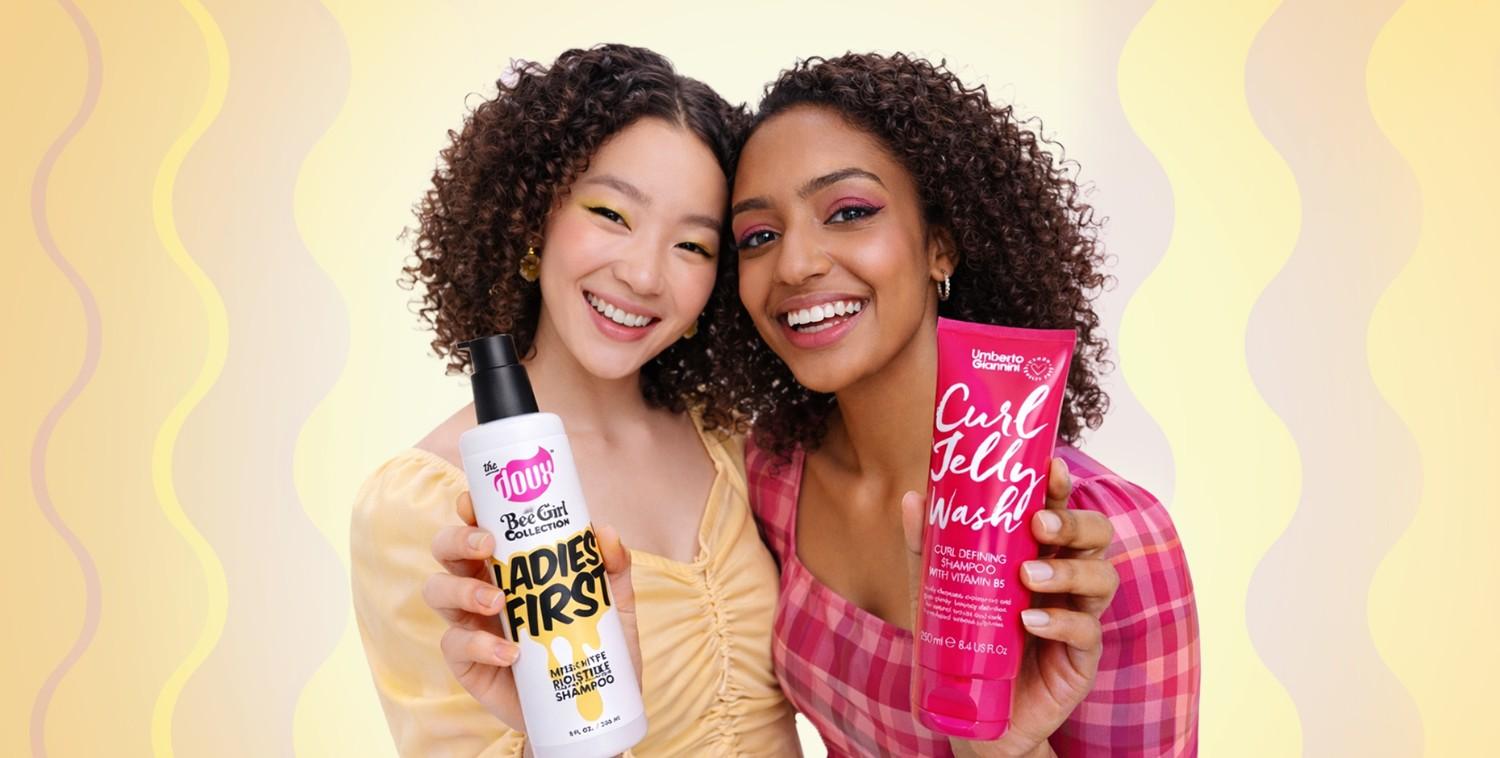 Two smiling women with curly hair holding up "Ladies First" shampoo and "Curl Jelly Wash!" products.