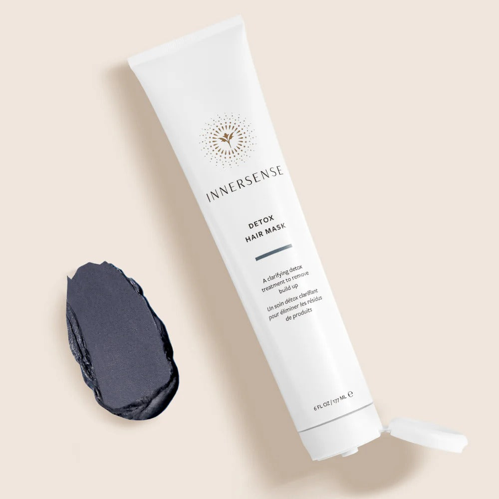 White Innersense Detox Hair Mask tube with an open cap, next to a dark gray charcoal mask swatch.