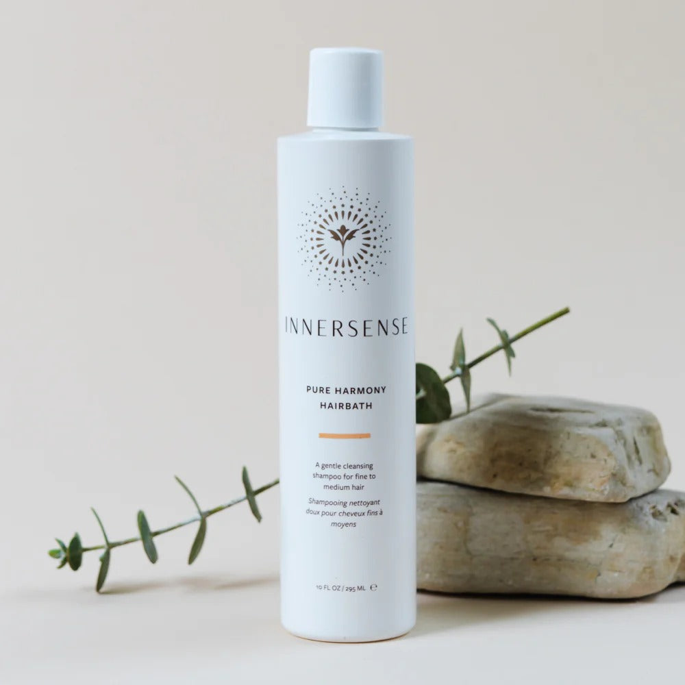 White Innersense Pure Harmony Hairbath bottle with gold sun logo, eucalyptus, and stacked stones.