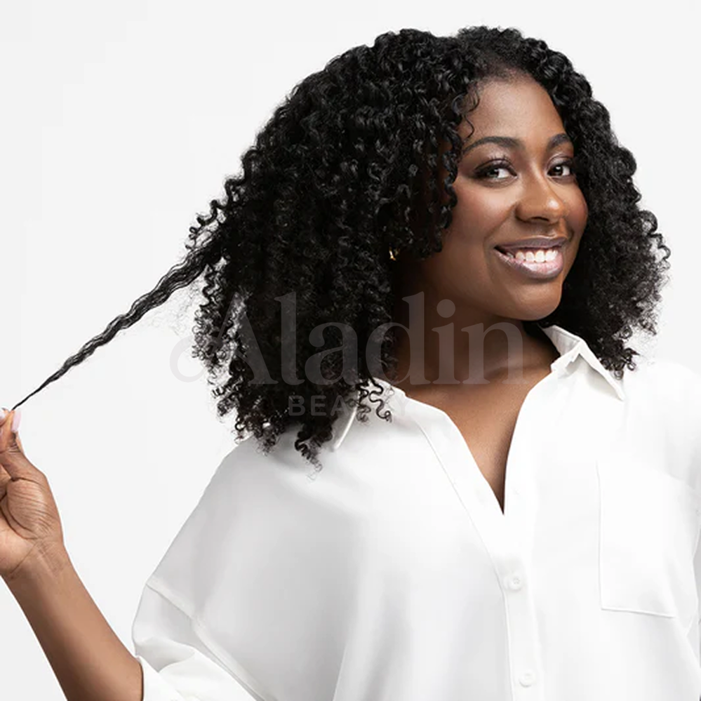 Smiling woman with defined, bouncy curls, holding out a stretched curl to show its length.