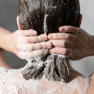 Person washing hair with hands covered in Shampoo