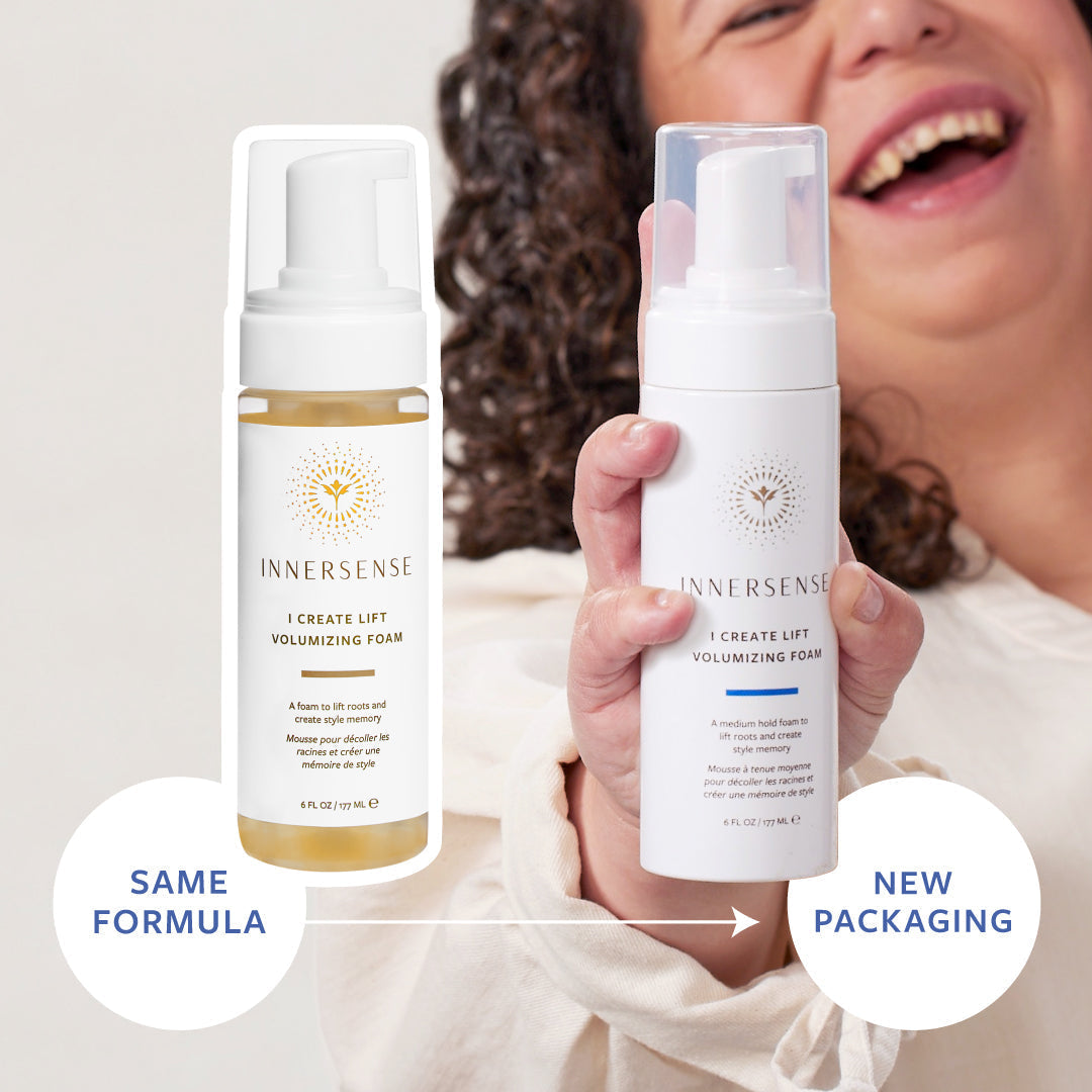 White Innersense I Create Lift Volumizing Foam bottle with a pump, held by a smiling person, next to the old packaging.