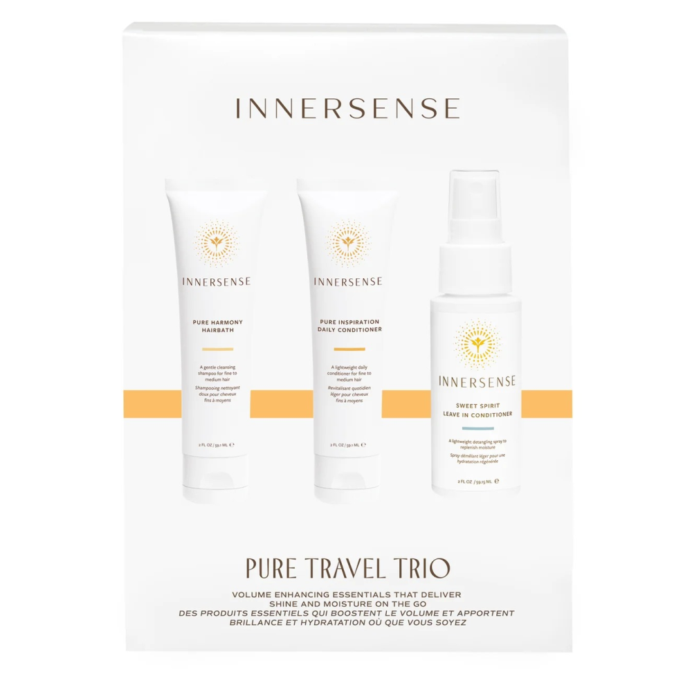 Three white Innersense Pure Travel Trio bottles: shampoo, conditioner, and leave-in spray, with gold sun logos.