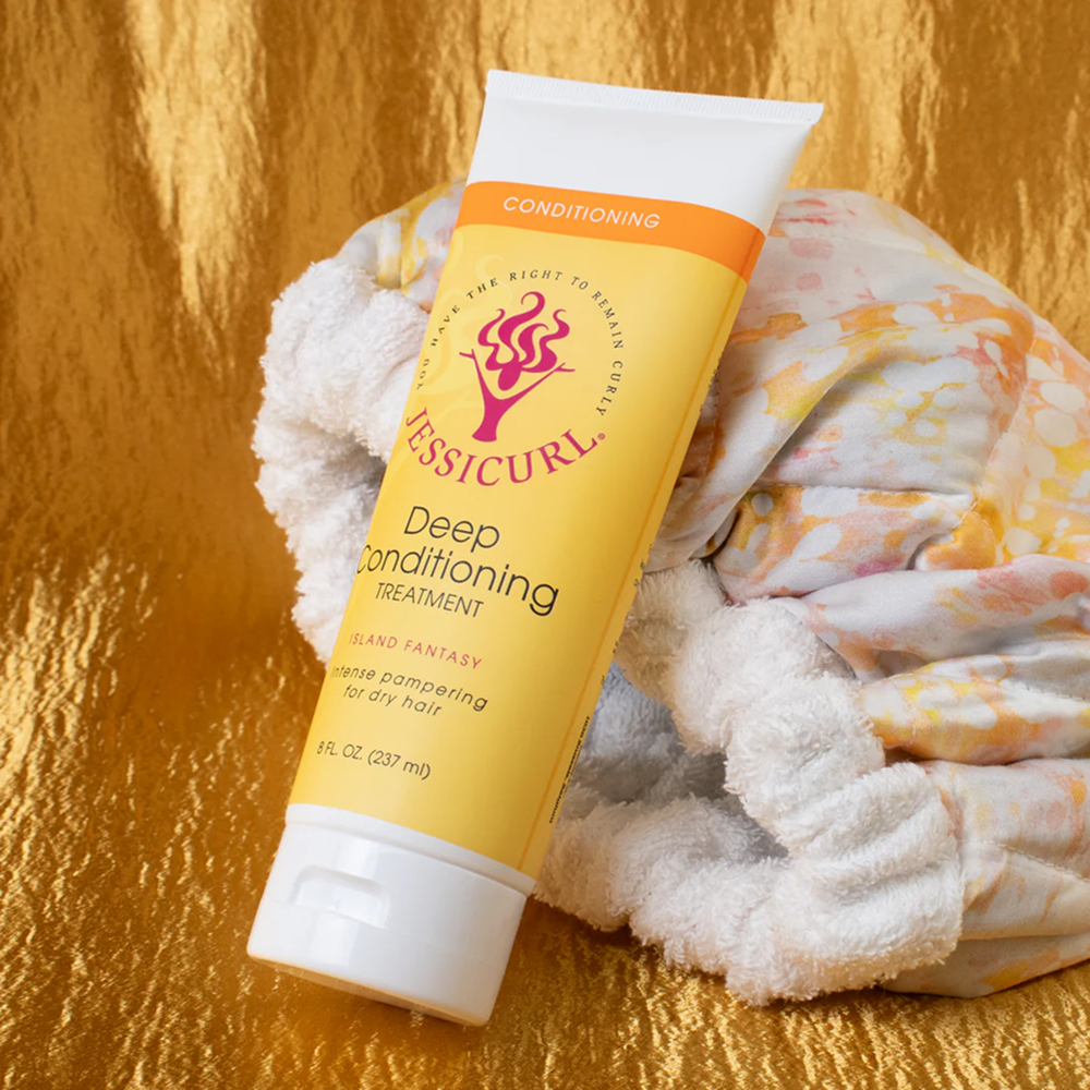 Yellow Jessicurl Deep Conditioning Treatment tube with orange accents, on a gold background with a white towel.