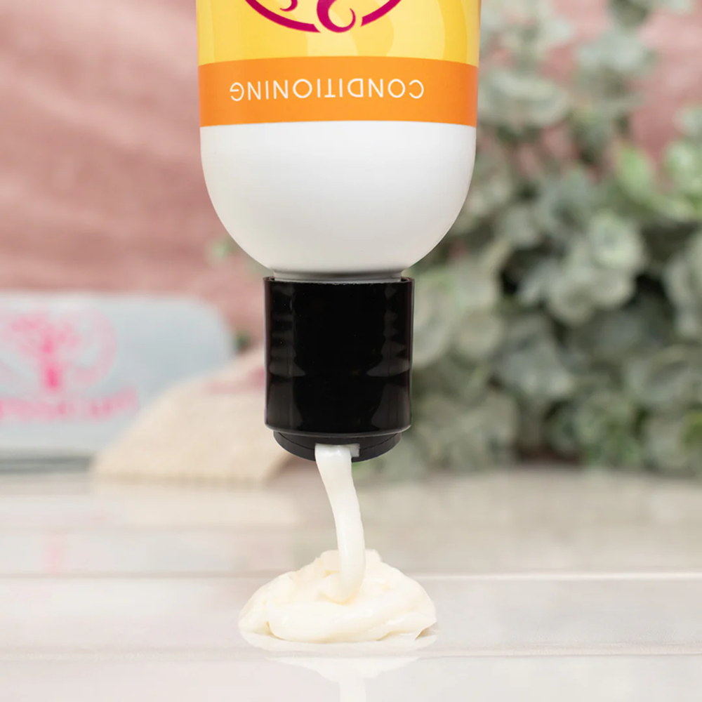 Jessicurl Too Shea! Extra Moisturizing Conditioner, white bottle with orange label, dispensing creamy product.